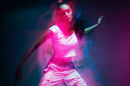 Colourful portrait of young mixed race girl dancing in studio. Long exposure. Colored neon light.の写真素材
