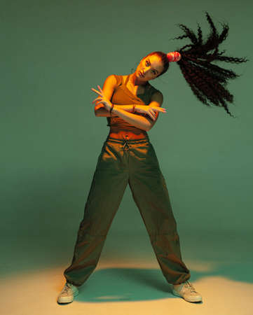 Confident young mixed race girl with afro hairs tail standing with waving hair in studio spotlightの写真素材