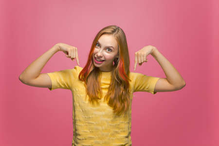 Excited happy young girl with open mouth pointing fingers down, surprised blogger show link with profitable offerの写真素材