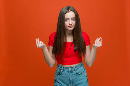 Modern young girl do money gesture with hands demanding cash payment and profit, reward payment on orange backgroundの写真素材