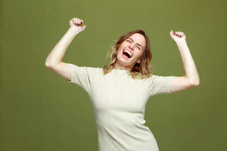 Overjoyed successful young woman celebrating win with raised arms, screaming with euphoria, happiness. Fortune conceptの写真素材