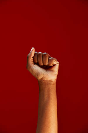 African american clenched fist raised up on red background. Black lives matter. Human rights fight, anti racism protestの写真素材
