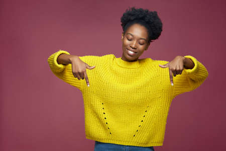 Attractive african american girl pointing fingers down advertise product or service, recommend link to subscribeの写真素材