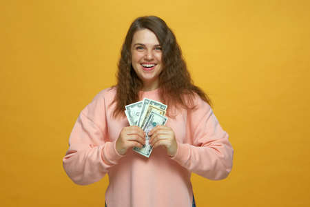 Financial success. Happy rich young girl holding cash, enjoying money win, big profit, wealthy life...