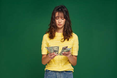 Worried sad young girl counting money. Frustrated female count banknotes cash, earnings. Lack of money, financial crisisの写真素材
