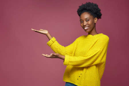 Smiling african american woman show empty copy space on open palms for advertising product or service. Good sale offerの写真素材