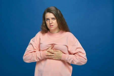 Sick young girl 20s clasping chest, suffering heart ache or breast pain, intercostal neuralgia on...