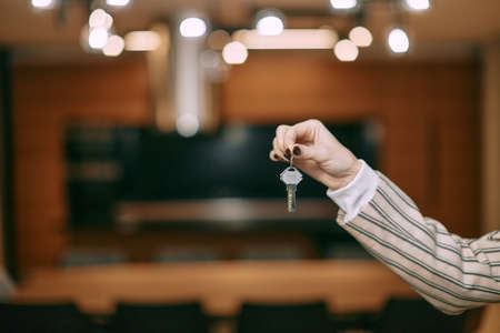 Keys from house flat apartment in hand of female realtor offering new real estate to potential buyer, close-upの写真素材