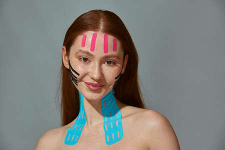 Face lift tape. Facelifting patches stickers for rejuvenating. Redhead girl satisfied with using of anti wrinkle tapesの写真素材