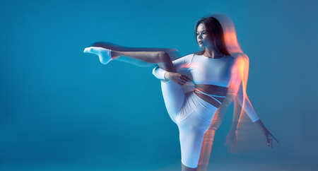 Pilates, yoga and stretching. Flexible slim young girl stretches her hip muscle, raised leg. Copy...