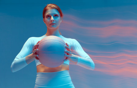 Athletic sports ambitious girl holds basketball pink ball in hands, looking at aim. Long exposure, motion blurの写真素材