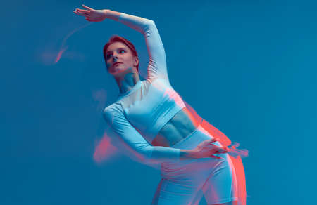 Young sports woman doing warm up exercise, makes side tilts. Long exposure, motion blur. Sport...