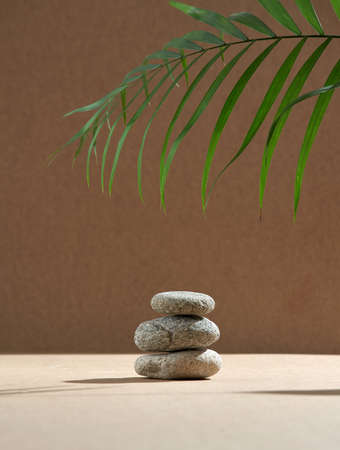 Stack of spa stones for massage, green palm leaf. Podium for natural ecofriendly cosmetics...
