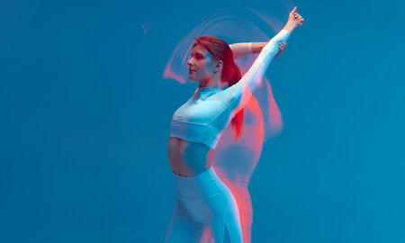 Fitness model slim girl raised hand, stretching back. Pilates workout. Long exposure, colorful neon light, copy spaceの写真素材
