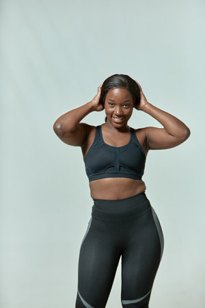 Happy african american girl wearing sportive clothes showing plus size hips, waist with fat folds. Body positive conceptの写真素材