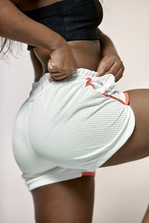 Body positive african american woman in sportswear. Sporty booty in sportive clothes. Girl tug sports shorts on buttocksの写真素材