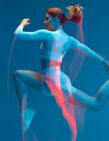 Sporty girl running in white tracksuit on blue background. Isolated fitness model in studio with motion blur effect.の写真素材