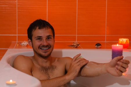 Beautiful young Bath man relaxing bathing in bathtube with bath foam during candle light の写真素材