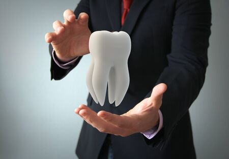 dental insurance concept: businessman protecting a tooth with his handsの写真素材