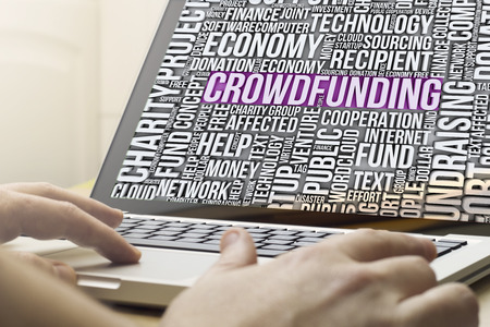 crowdfunding concept: man using a laptop with crowdfunding cloud words on the screenの写真素材