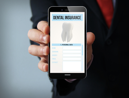 new technologies business concept: businessman hand holding a 3d generated touch phone with dental insurance on the screen.の写真素材