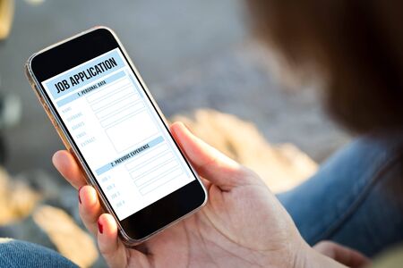 close-up view of young woman holding a smartphone with job application on screen. All screen...