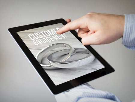 new technologies concept: hands with touchscreen tablet with customer engagement on the screen. Screen graphics are made up.の写真素材