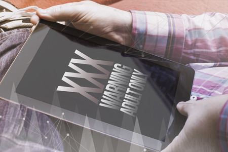 close-up view of man holding a tablet showing adult porn site. Digital porn industry concept. All screen graphics are made up.の写真素材