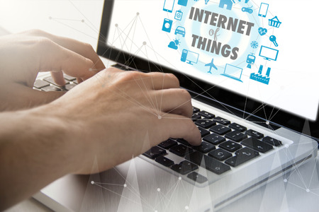 technology and business concept: man using a laptop with internet of things concept on the screen. All screen graphics are made up.の写真素材