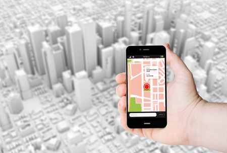 Hand hold a smartphone with GPS map on a screen on the background of a 3D city.