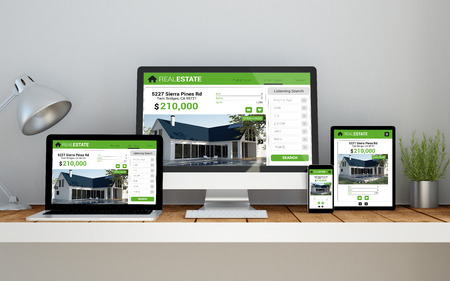 A computer, laptop, smartphone and tablet on a desktop workspace with real estate online responsive...