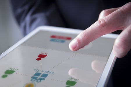 Hand interacting with application to split expenses between friends on the screen of a tablet. All graphics are made up.の写真素材