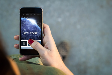 Top view of woman walking in the street using her mobile phone with copy space. All screen graphics are made up.の写真素材