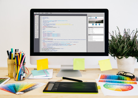 Stationery desktop with design stuff, computer and graphic tablet. website code design.