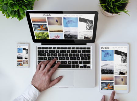 office tabletop with tablet, smartphone and laptop showing photo portfolio websiteの写真素材