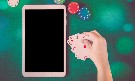 cards, chips and black screen tablet over poker table