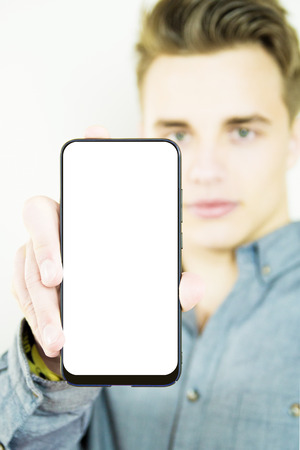 Handsome millennial showing generic blank full screen smartphoneの写真素材