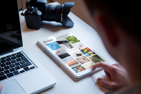 Photographer checking online portfolio on a tabletの写真素材