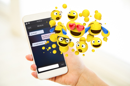 Woman holding a pink gold generic smartphone showing chat app and emoticonsの写真素材