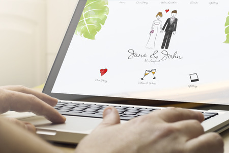 online business concept: man using a laptop with wedding website on the screen. Screen graphics are made up.の写真素材