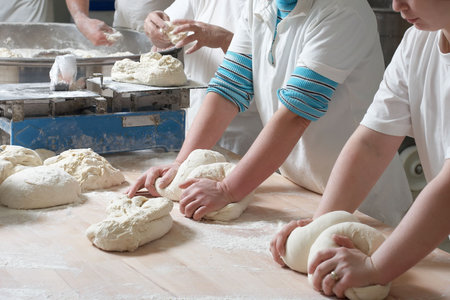 Women bakery team at work weigh and mixing doughの写真素材