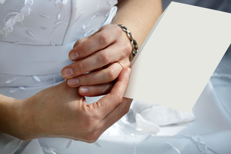 Young bride holding paper between her fingersの写真素材