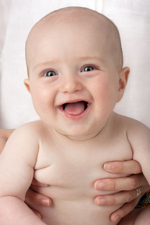 Joyful baby held by his mother's handsの写真素材