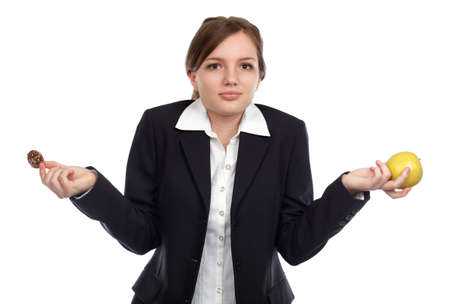 Young woman undecided what to choose between apple and chocolate cookiesの写真素材