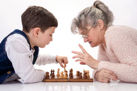 Grandma and nephew face to face playing chessの写真素材