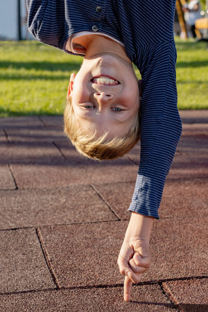 Boy upside down leaning on a finger outoors in the park. Concept for young people who do things...