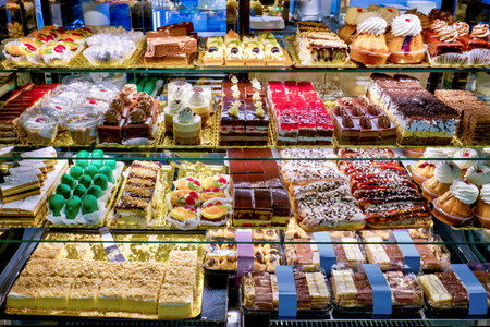 Showcase with four shelves full of various tasty and beautifully colored cakesの写真素材