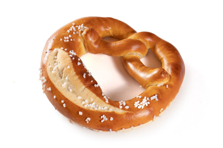 A Bavarian pretzel with salt on a white background. The pretzel is shaped like a knot and covered in a generous amount of salt. The pretzel is golden brown in color and looks crunchy and delicious.の写真素材