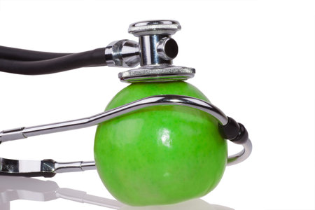 Medical stethoscope and apple isolated on whiteの写真素材