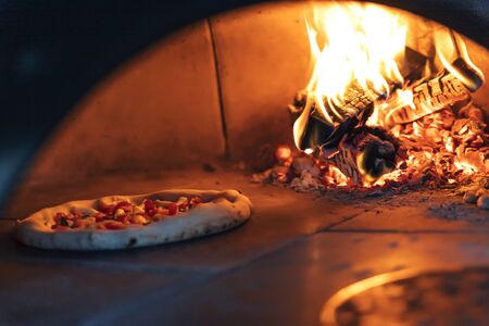 Pizza is baked in the oven near the burning wood. Neapolitan pizzaの写真素材